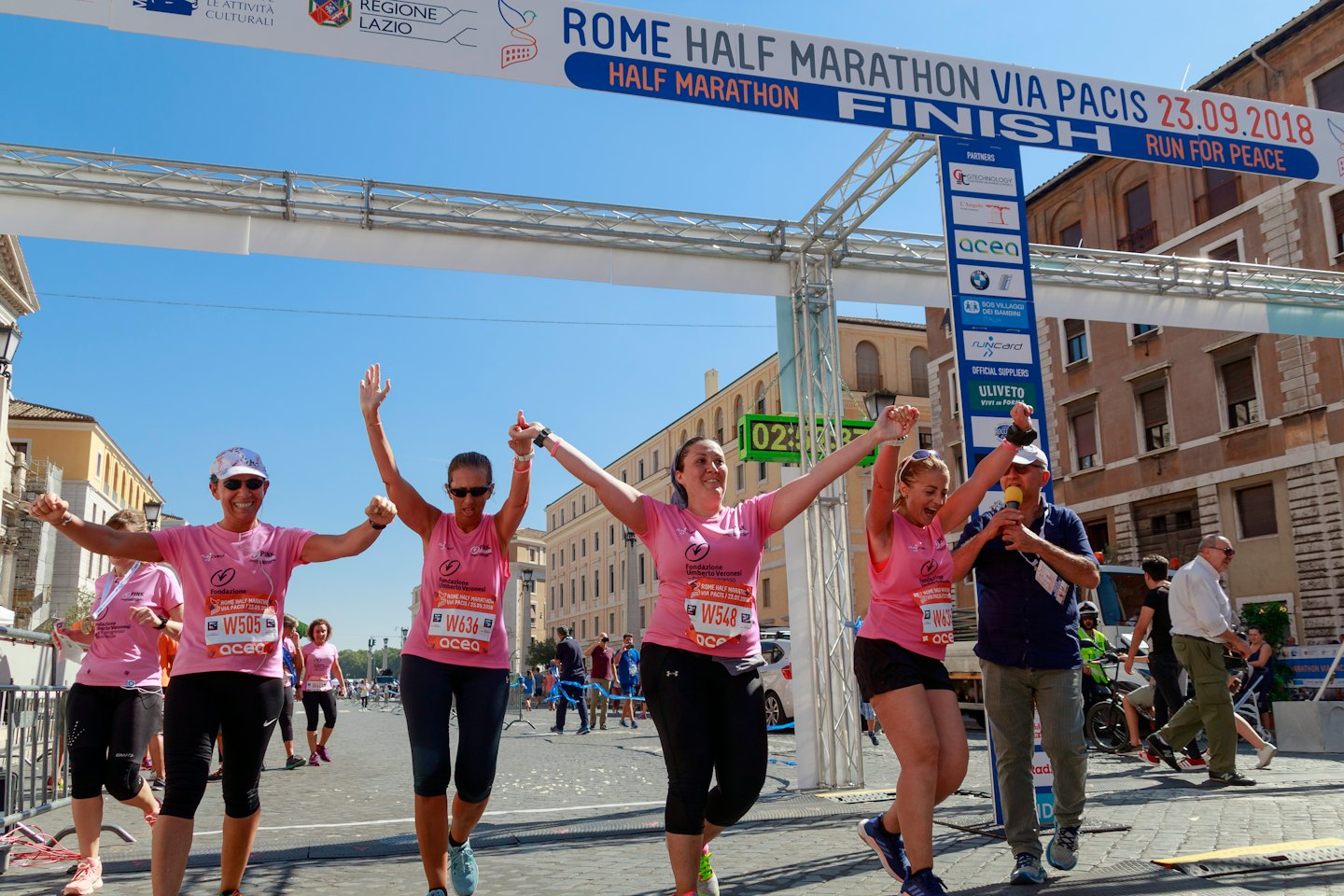 Mujeres de rosa cruzan la meta de media maratón.
